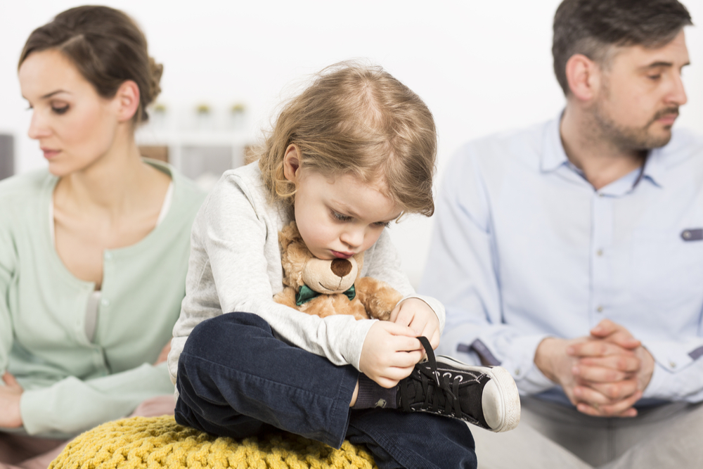 A baby sitting in the middle of a divorced couple
