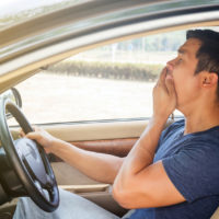 asian man yawning while driving