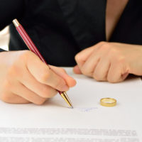 Wife signing divorce agreement with wedding ring on contract Wife signing divorce agreement with wedding ring on contract