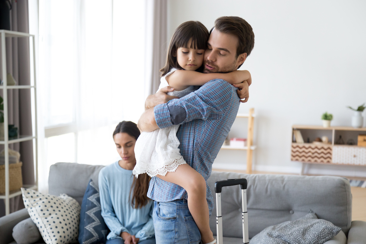 little girl hugging dad with mom in background