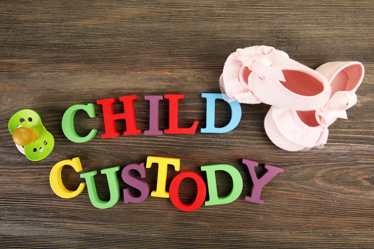 Baby’s booties, dummy and colourful letters regarding child-custody and family-law concept