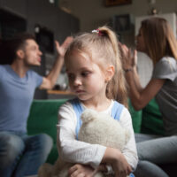 Kid daughter feeling upset while parents fighting at background