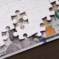 American dollar hidden under puzzle pieces American dollar hidden under puzzle pieces