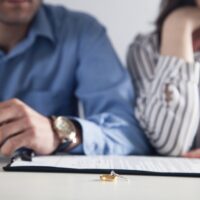 Couple with divorce contract and ring on desk. Divorce