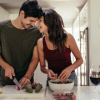 Loving couple cutting vegetables together in kitchen Loving couple cutting vegetables together in kitchen