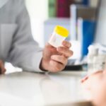 Doctor, patient and urine test cup. Physician giving pee container to a woman in clinic or hospital emergency room. Urinary sample for medical exam in hospital. Checkup for infection or salmonella.