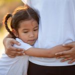 Sad child girl hugging her mother in the paddy field with the sunlight