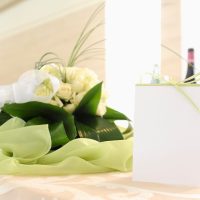 Placeholder with green ribbon on a table with a bouquet of white roses in the background to understand the concept of celebration