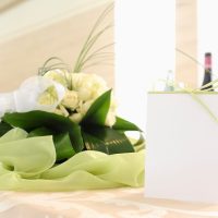 Placeholder with green ribbon on a table with a bouquet of white roses in the background to understand the concept of celebration Placeholder with green ribbon on a table with a bouquet of white roses in the background to understand the concept of celebration