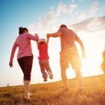 girl with mother and father holding hands on the nature. Child with parents outdoors