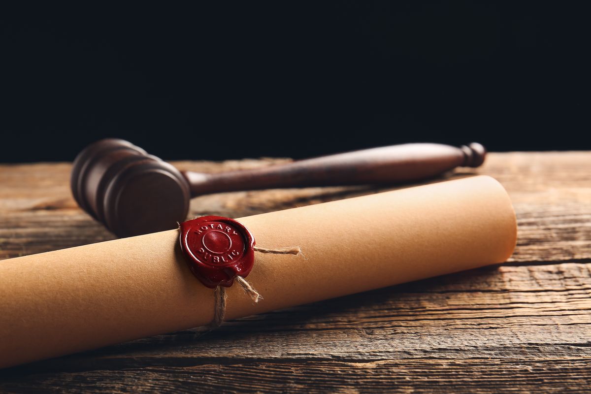 Scroll with notary public wax seal and gavel on table