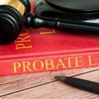 Close-up view of a red book titled "PROBATE LAW in gold lettering. A black judge's gavel with a gold band rests on top.