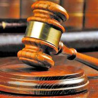 Close-up of a gavel resting on a wooden desk