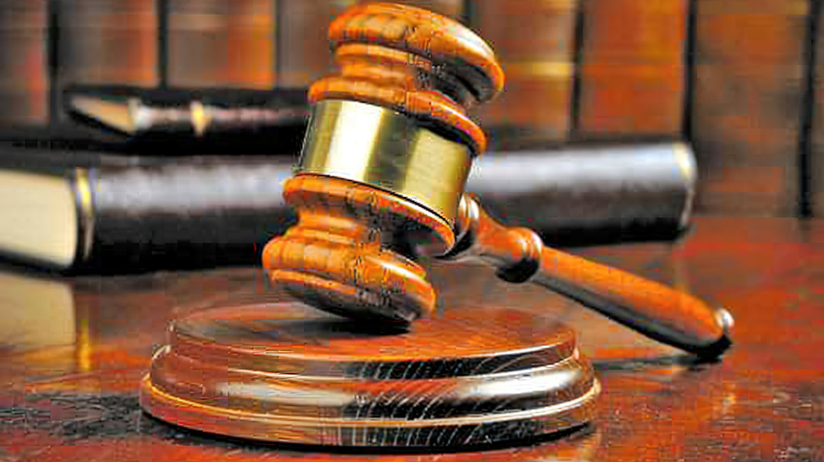 Close-up of a gavel resting on a wooden desk