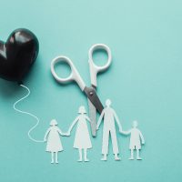 White scissor cutting family paper cut out holding black heart balloon on blue background, causes and effects on child development and behavior of dysfunctional family, divorce parent broken home concept, mental health