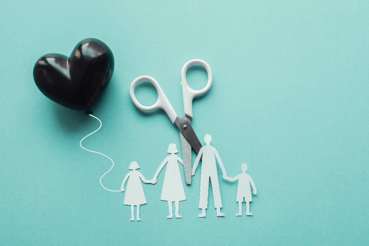 White scissor cutting family paper cut out holding black heart balloon on blue background, causes and effects on child development and behavior of dysfunctional family, divorce parent broken home concept, mental health