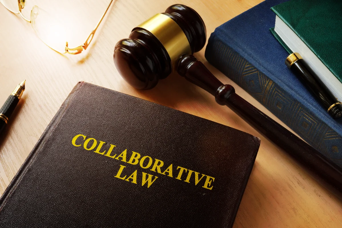 A law-themed desk with a "Collaborative Law" book, a wooden gavel, glasses, and pens. The scene conveys professionalism and legal focus.