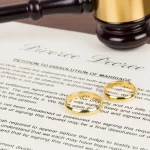 Wooden judge gavel, golden rings, and divorce decree; document is mock-up