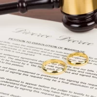 Wooden judge gavel, golden rings, and divorce decree; document is mock-up Wooden judge gavel, golden rings, and divorce decree; document is mock-up